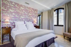 a bedroom with a large bed with a pink wall at Suites Murillo Alcázar in Seville