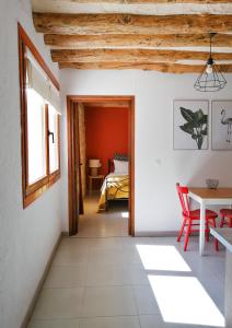 FuentespaldaにあるApartamentos Mas de Pauの白い壁の客室で、テーブルと赤い椅子が備わります。