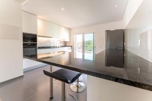 Una cocina con gabinetes blancos y una encimera negra. en Apartamento T2 Kress Property, en Pederneira