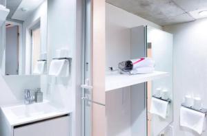 La salle de bains blanche est pourvue d'un lavabo et d'un miroir. dans l'établissement japan house nishishinjuku, à Tokyo