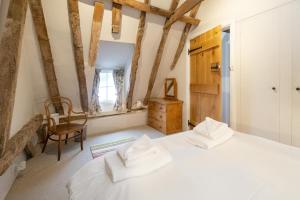 a bedroom with a white bed and a chair at White Cottage, Iken - Aldeburgh Coastal Cottages in Snape