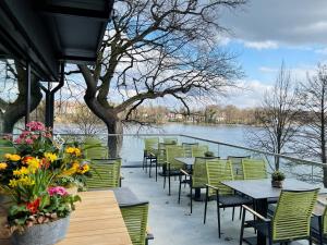 a patio with tables and chairs next to a body of water at Zweirad Hotel Lenne in Schwerin