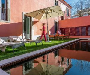 una persona caminando por una piscina con sombrilla en Rosegarden House - by Unlock Hotels, en Sintra