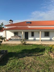 een gebouw met een rood dak en een bank voor de deur bij Moradia Gémea em Herdade Santa Marta in Zebreira