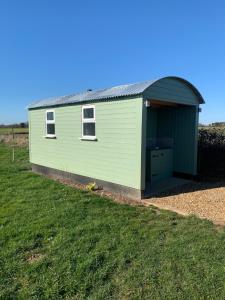 a green building with a garage in a field at Maple Hut Four Acre Farm in Aylsham