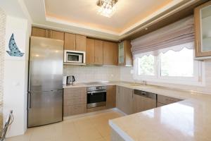 a kitchen with a stainless steel refrigerator and a window at Mira Mare Beachfront Villa in Nea Skioni