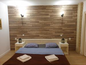 a bedroom with a wooden accent wall with two tables and a bed at Bizant Boutique in Bacău