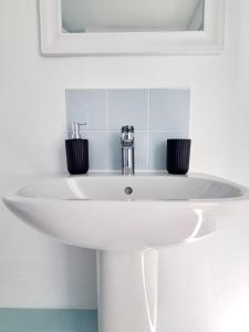 a white sink in a bathroom with a mirror at Visit Seaford Apartment - 4 Bedrooms in Seaford