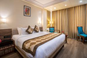 una habitación de hotel con una cama grande y sillas azules en Spree Hotel Jaipur, en Jaipur 29 fotos más