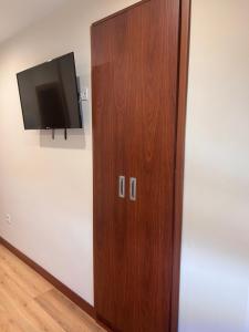 a wooden door with a flat screen tv on a wall at Hostal Avenida in Benavente
