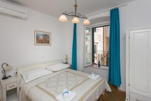 a bedroom with a bed with blue curtains and a window at Lumin Guest House in Dubrovnik