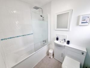 a bathroom with a toilet and a shower and a sink at Visit Seaford Apartment - 4 Bedrooms in Seaford