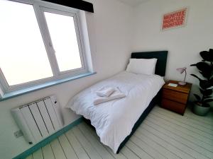 a bedroom with a bed with white sheets and a window at Visit Seaford Apartment - 4 Bedrooms in Seaford