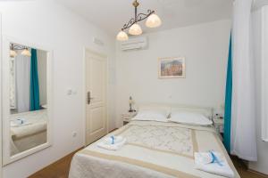 a white bedroom with a bed and a mirror at Lumin Guest House in Dubrovnik