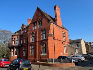 a red brick building with cars parked in front of it at Red Gables - Ground Floor in Carlisle