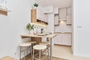 a kitchen with white cabinets and bar stools at Apartment Krakowska 39 with AC & PARKING & LOGGIA Wrocław by Renters in Wrocław
