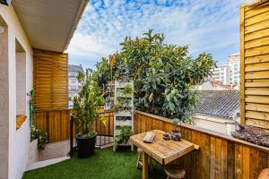 a patio with a wooden table and plants on a fence at Le Néflier Dijon - appart balnéo - SPA romantique pour 2 in Dijon