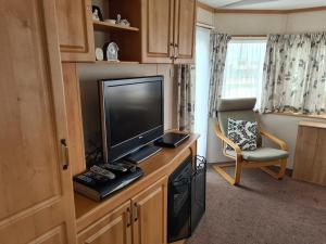 sala de estar con TV y silla en 6 Berth Kingfisher (Firs) en Ingoldmells