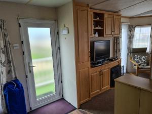 a living room with a tv and a sliding door at 6 Berth Kingfisher (Firs) in Ingoldmells