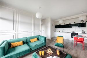 a living room with a green couch and a kitchen at Waw Apartamenty Wilanów Sarmacka in Warsaw