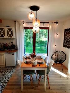 a dining room with a table and chairs and a kitchen at Między Brzozami in Pluski