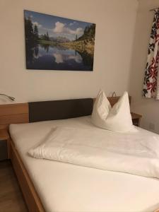 a bed with white sheets and a picture on the wall at Panoramablick Tscheltsch in Liesing