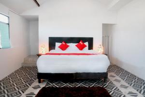 - une chambre avec un grand lit blanc et des oreillers rouges dans l'établissement OYO Hotel Maria Otilia Falla, Papantla, à Papantla