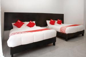 - 2 lits dans une chambre avec des oreillers rouges dans l'établissement OYO Hotel Maria Otilia Falla, Papantla, à Papantla