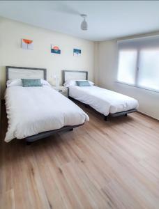 two beds in a room with wooden floors at DOMVS II in El Burgo de Osma