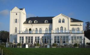 a large white building with people sitting on a balcony at Haus Bischofsstab - Ferienwohnung am Meer in Heiligendamm