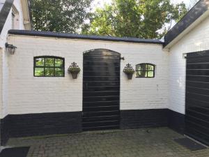 a white building with a black door and two windows at Atelier Onder de Notenboom in Appeltern