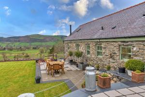 a stone house with a patio with a table and chairs at Finest Retreats - Moelis Granary - Luxury Cottage with Hot Tub in Llandrillo