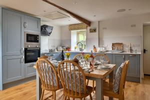 a kitchen with a wooden table and chairs in a kitchen at Finest Retreats - Moelis Granary - Luxury Cottage with Hot Tub in Llandrillo