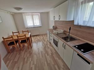 - une cuisine avec des placards blancs, une table et des chaises dans l'établissement Apartments Henigman, à Bohinj