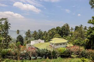 a house with a green roof in a garden at The Flame Tree Estate & Hotel in Kandy