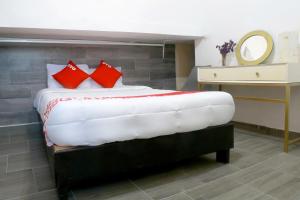 - une chambre avec un lit doté d'oreillers rouges et d'un miroir dans l'établissement OYO Hotel Maria Otilia Falla, Papantla, à Papantla