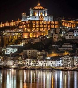 un edificio iluminado en una colina junto al agua en Casa dos Sequeiras Port Wine Cellars, en Vila Nova de Gaia