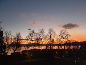 a sunset with trees in front of a body of water at Villa & Apartments Antigona in Ohrid