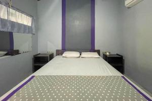 Cama en habitación con paredes moradas y cama sidx sidx sidx sidx en Mbah Mek Trawangan Homestay, en Gili Trawangan