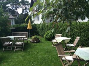 einen Garten mit Tischen, Stühlen und einem Sonnenschirm in der Unterkunft B&B Elfi in Salzburg