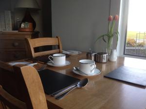un tavolo di legno con due tazze e cucchiai sopra di Glanllifon B&B a Criccieth