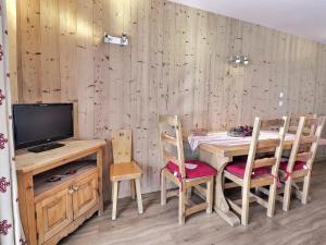 ein Esszimmer mit einem Tisch, Stühlen und einem TV in der Unterkunft Appartement Méribel, 2 pièces, 4 personnes - FR-1-182-51 in Méribel