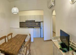 a dining room with a wooden table and a kitchen at Residence Capobianco in Portoferraio