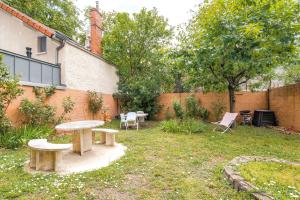 a backyard with two benches and a table and a tree at Appart-Hotel Métro D Mermoz Lyon8 in Lyon