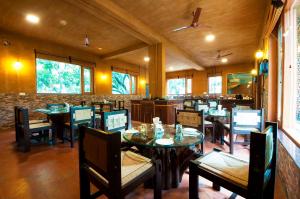 uma sala de jantar com mesas e cadeiras num restaurante em Tuskars Riverside Resort Jim Corbet em Rāmnagar