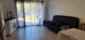 a living room with a black couch and a window at Bas de maison de village cosy & relax in Vero