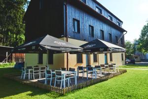 a group of tables and chairs with umbrellas in front of a building at Stodola na Bílé in Bílá