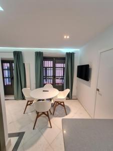 Un comedor con mesa y sillas y un televisor. en DreamsApt Sierpes, en Sevilla