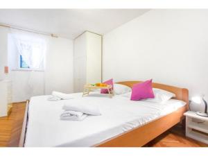a bedroom with a bed with white and pink pillows at Apartment Primosten Center in Primošten