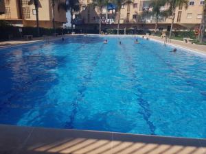 - une grande piscine bleue avec des personnes dans l'établissement Orly Pobla de Farnals playa, à Las Canteras